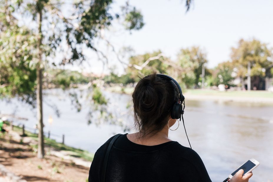 woman listening to sound recordings through mobile device and earphones