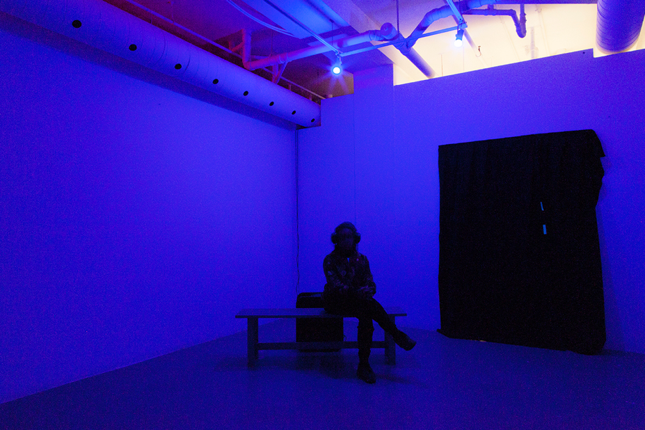 person with headphones sitting on bench in art gallery